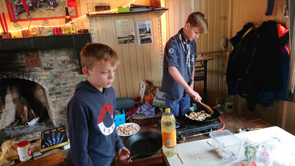 De scouts of zeeverkenners maken champignons klaar op gasvuur bij leuke activiteit